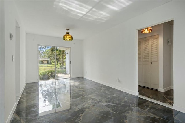 unfurnished room featuring marble finish floor and baseboards