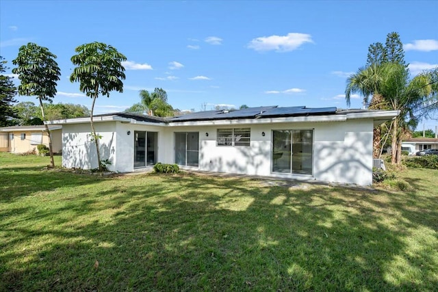 back of house featuring a yard and roof mounted solar panels