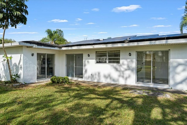 back of property with stucco siding and a yard