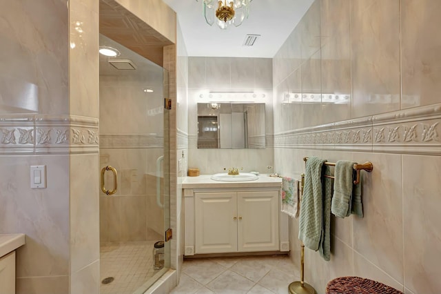 bathroom with tile patterned flooring, vanity, a shower with door, and tile walls