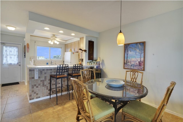 tiled dining room with ceiling fan and sink