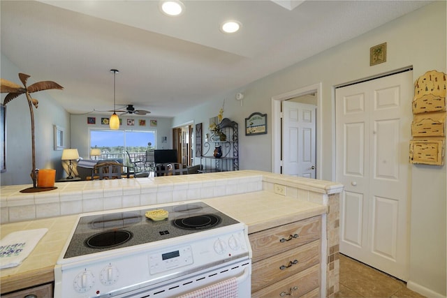 kitchen featuring white range oven, ceiling fan, tile counters, and light tile patterned floors