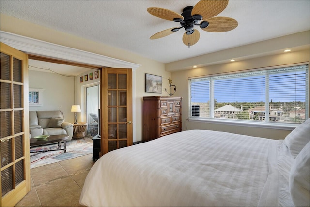 bedroom featuring ceiling fan, light tile patterned floors, and a textured ceiling