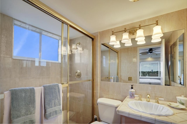 bathroom featuring ceiling fan, a shower with door, vanity, and tile walls