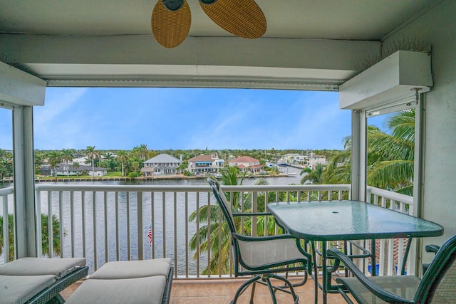 balcony with ceiling fan and a water view