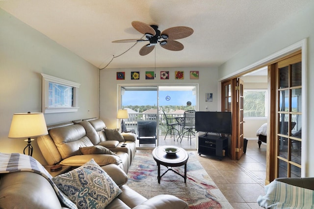 tiled living room featuring vaulted ceiling, ceiling fan, and a textured ceiling