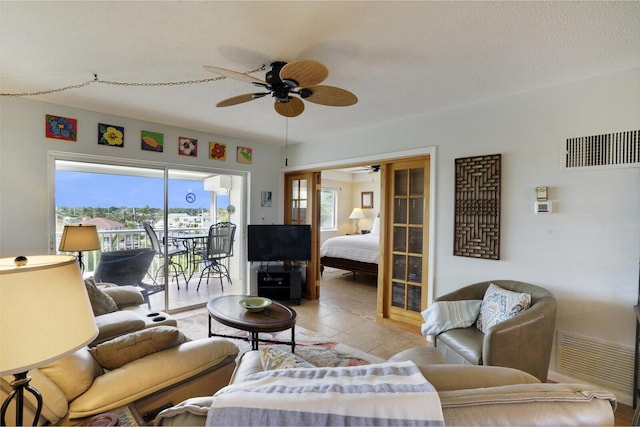 living room featuring plenty of natural light, ceiling fan, light tile patterned floors, and a textured ceiling