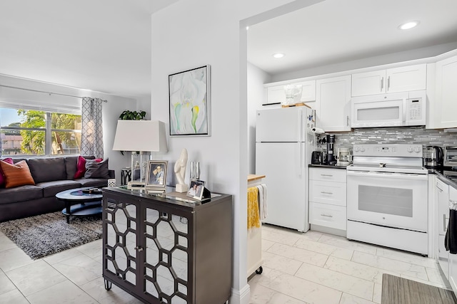 kitchen with white cabinets, decorative backsplash, and white appliances