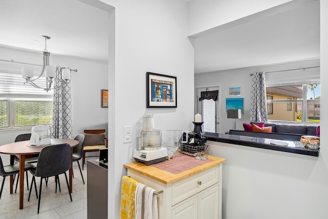 kitchen featuring wooden counters, decorative light fixtures, an inviting chandelier, and plenty of natural light