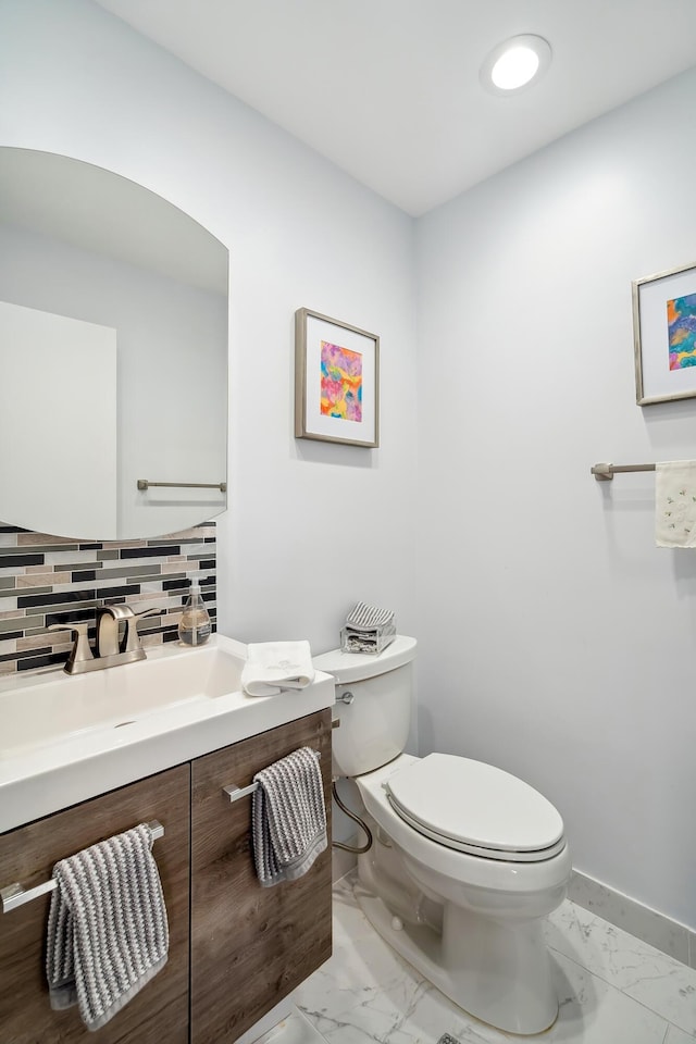 bathroom featuring vanity, toilet, and backsplash