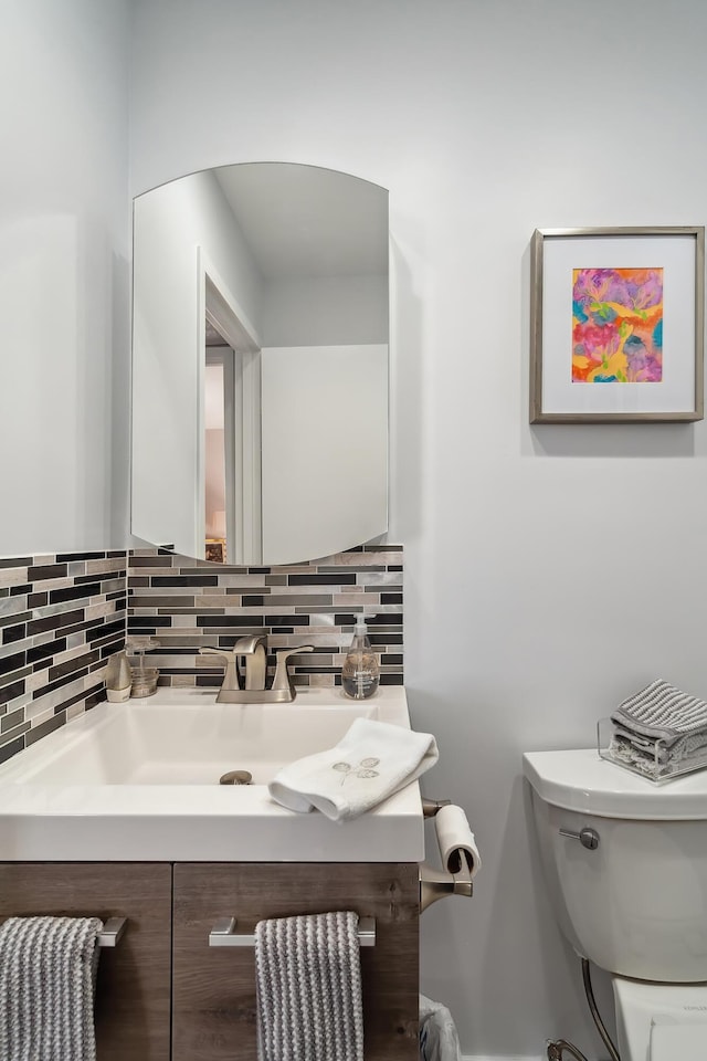 bathroom with decorative backsplash, toilet, and vanity