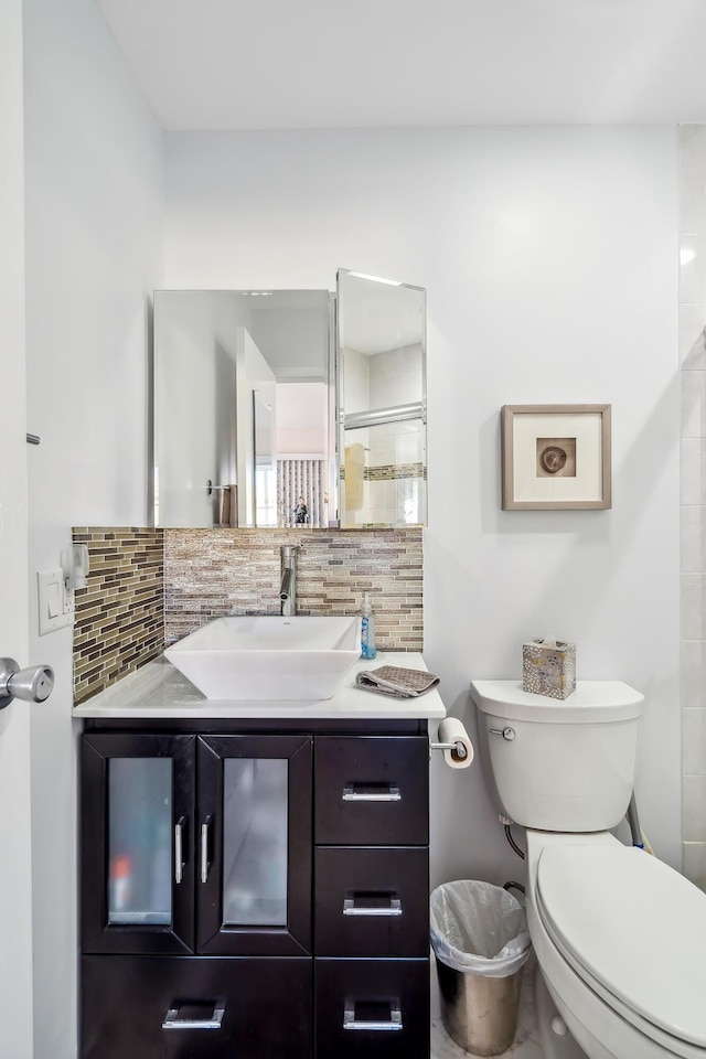 bathroom with backsplash, vanity, an enclosed shower, and toilet