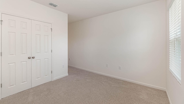 unfurnished bedroom with light carpet and a closet