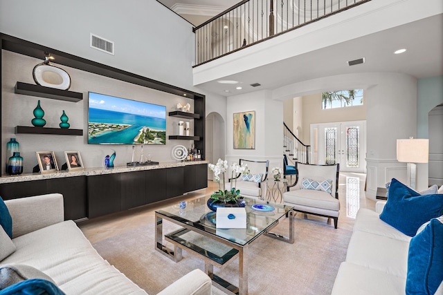 living room featuring stairway, visible vents, arched walkways, and a decorative wall