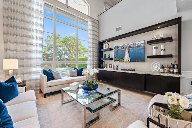 living room with a dry bar, a towering ceiling, and visible vents