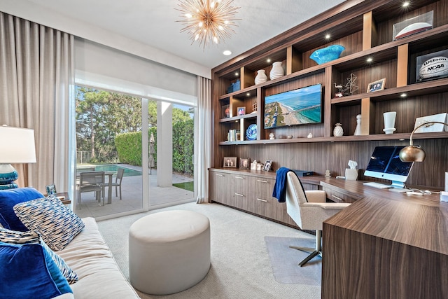 office space with built in shelves, a chandelier, built in study area, and light colored carpet