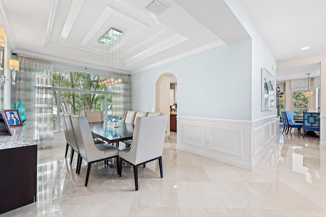 dining area featuring arched walkways, a decorative wall, visible vents, wainscoting, and a tray ceiling