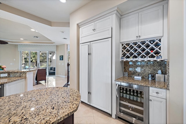 kitchen featuring beverage cooler, white cabinetry, visible vents, and light stone countertops