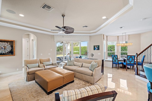 living room with arched walkways, a tray ceiling, and visible vents