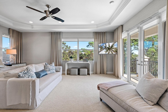 carpeted living room with ornamental molding, a tray ceiling, french doors, and a ceiling fan