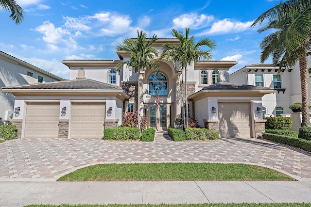 view of front of home featuring a garage, a tile roof, stone siding, decorative driveway, and stucco siding