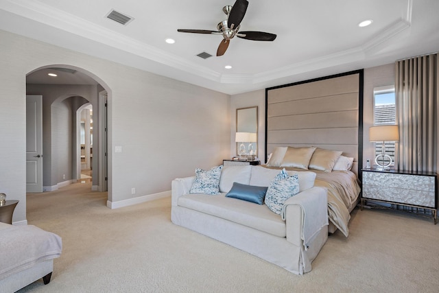 bedroom featuring light carpet, visible vents, arched walkways, a raised ceiling, and ornamental molding