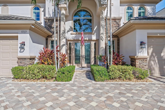 view of exterior entry featuring an attached garage and stucco siding