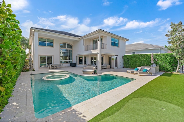 back of house with a patio, a balcony, an in ground hot tub, fence, and stucco siding