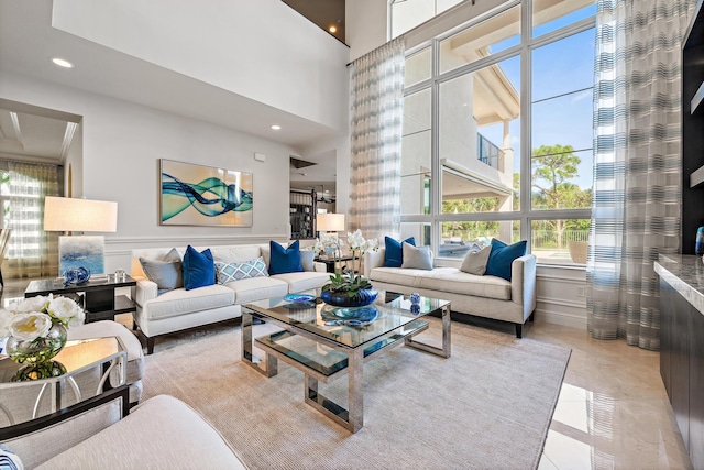 living room featuring light tile patterned floors, wainscoting, a high ceiling, and recessed lighting