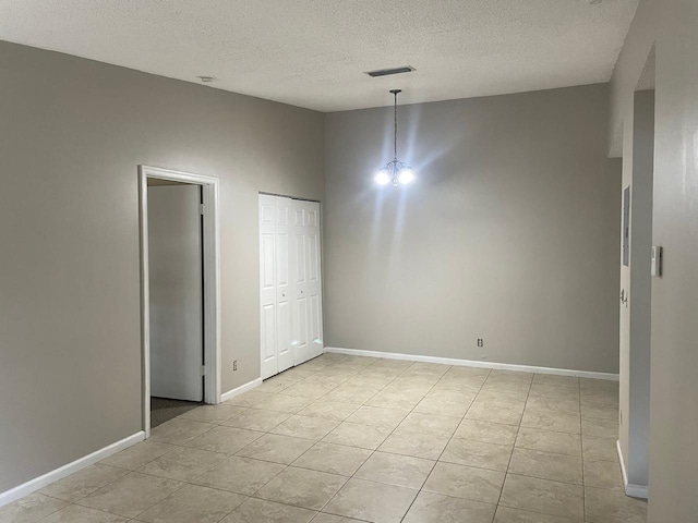 unfurnished room featuring a textured ceiling, light tile patterned floors, and baseboards