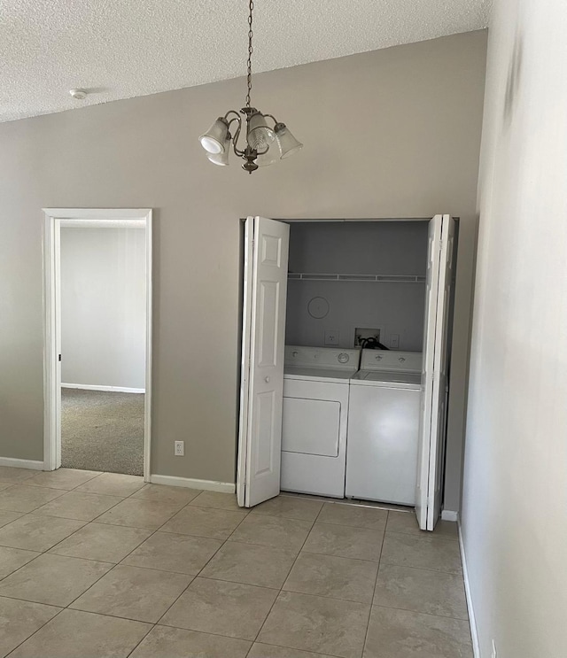 laundry room with washer and dryer, a chandelier, a textured ceiling, light tile patterned floors, and baseboards