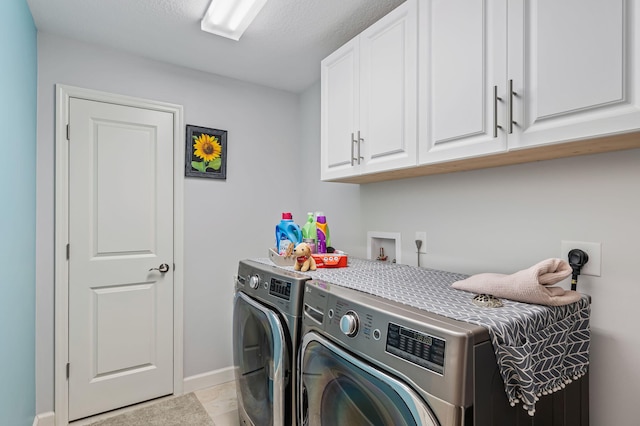 laundry room featuring washer and clothes dryer, light tile patterned floors, cabinets, and a textured ceiling