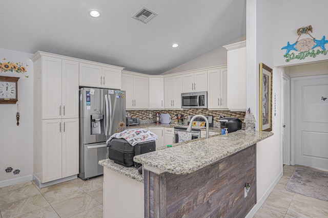 kitchen with white cabinets, light stone countertops, kitchen peninsula, and appliances with stainless steel finishes