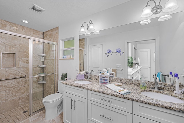 bathroom with vanity, tile patterned floors, toilet, a textured ceiling, and a shower with shower door