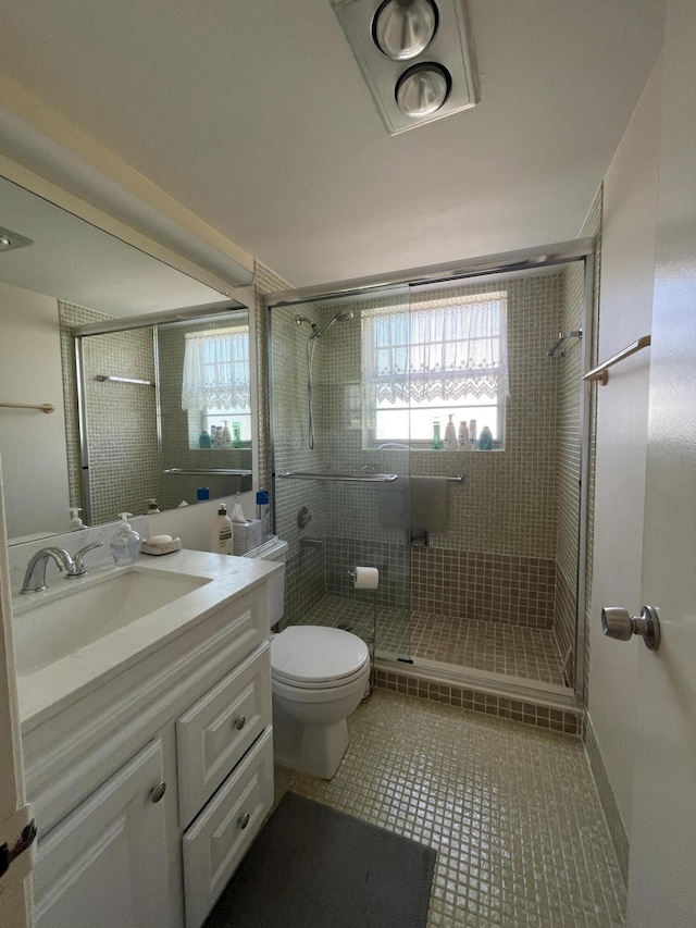 bathroom with tile patterned floors, vanity, toilet, and a shower with shower door