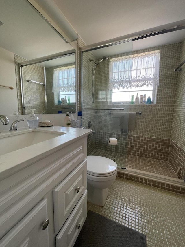 bathroom featuring vanity, a shower with door, toilet, and plenty of natural light