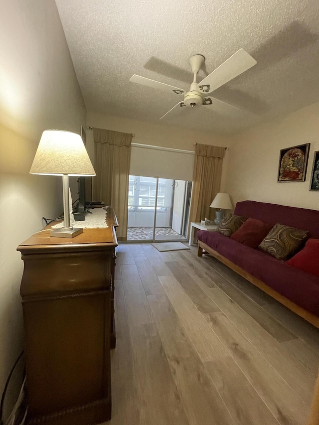 living room with a textured ceiling, hardwood / wood-style flooring, and ceiling fan