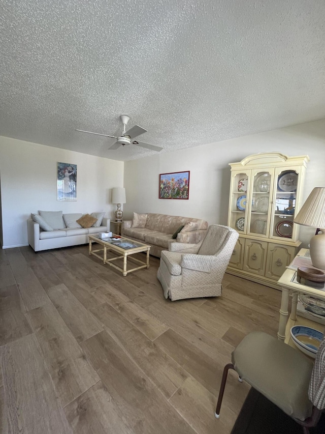 living room with hardwood / wood-style floors, ceiling fan, and a textured ceiling