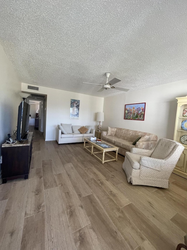 living room featuring ceiling fan, a textured ceiling, and hardwood / wood-style flooring