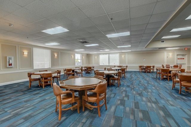 carpeted dining area with a paneled ceiling