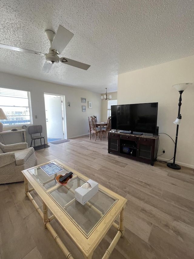 living room with ceiling fan with notable chandelier, a textured ceiling, and hardwood / wood-style flooring