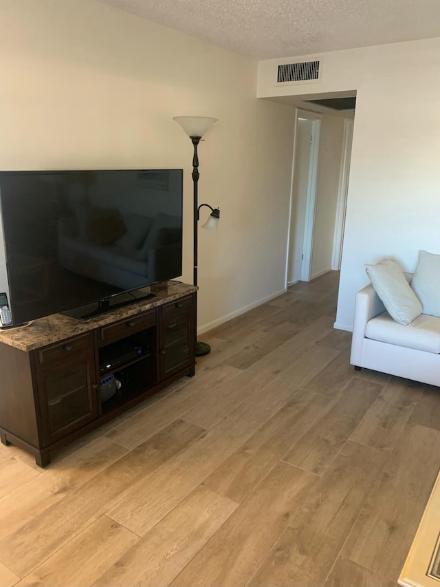 living room featuring a textured ceiling and light hardwood / wood-style flooring