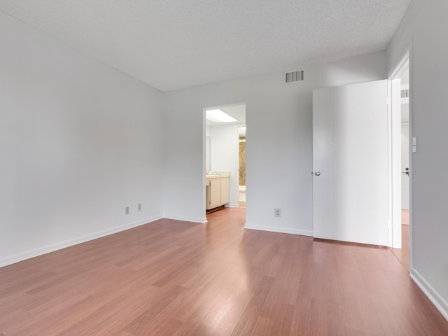 spare room featuring light hardwood / wood-style flooring and a textured ceiling