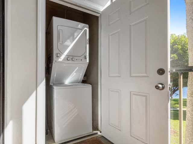 laundry room with stacked washer / drying machine and a healthy amount of sunlight