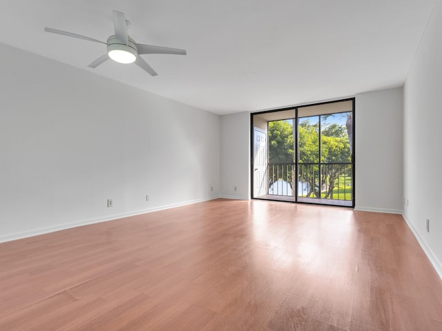 unfurnished room with expansive windows, light hardwood / wood-style flooring, and ceiling fan