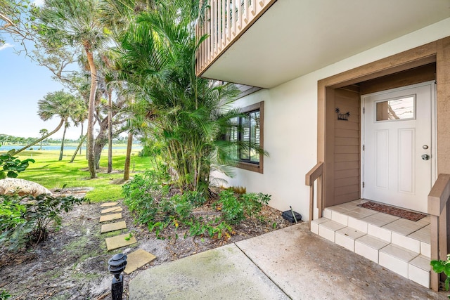 view of exterior entry with a balcony and a yard