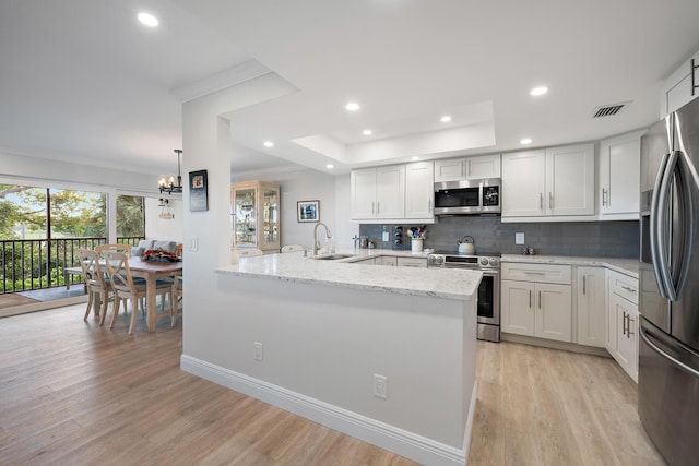 kitchen with backsplash, white cabinets, light wood-type flooring, and appliances with stainless steel finishes