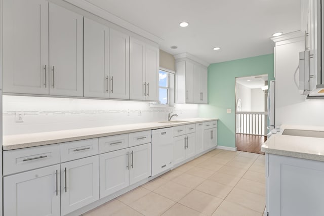 kitchen with tasteful backsplash, white appliances, sink, white cabinetry, and light tile patterned flooring