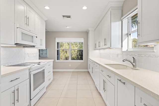 kitchen with white appliances, backsplash, white cabinets, sink, and light tile patterned floors