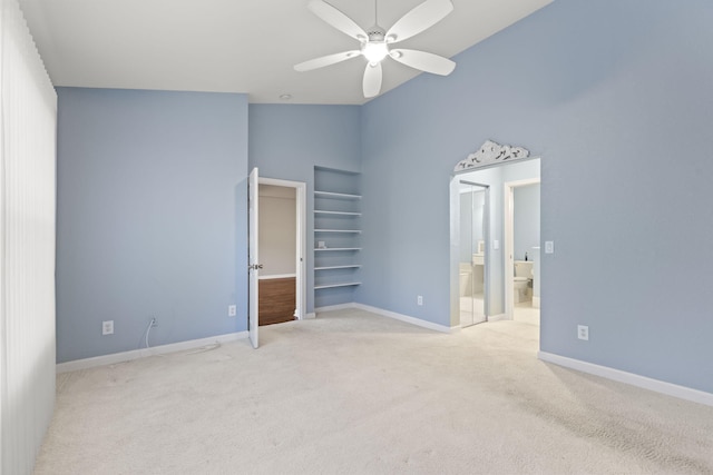 unfurnished bedroom featuring ceiling fan, light colored carpet, and ensuite bath